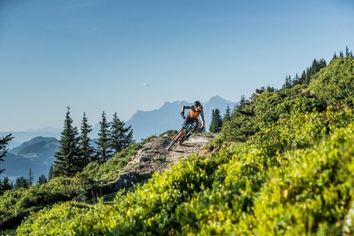 Seit Anbeginn des Mountainbike Sports in Österreich waren Saalbach Hinterglemm und Saalfelden Leogang Vorreiter in Sachen Bike-Trails und Infrastruktur. Die Region, die durch den Zusammenschluss zum Skicircus Saalbach Hinterglemm Leogang Fieberbrunn im Winter längst zu einem der modernsten und größten Skigebiete Europas gewachsen ist und seit Jahren erfolgreich zusammenarbeitet, hat 2020 auch im Sommer den Schritt gewagt. Saalbach Hinterglemm, Saalfelden Leogang und Fieberbrunn verbünden sich zu Österreichs größter Bike-Region!
              Lange betrachtete man Saalbach Hinterglemm und Saalfelden Leogang als zwei eigenständige Bike-Destinationen. Lange haben sich die beiden Regionen in Sachen Bike-Angebot gegenseitig motiviert zu wachsen. Und lange wurde an einem gemeinsamen Angebot und dem Zusammenschluss gefeilt. Und um dem Biker das größtmögliche Mountainbike-Wegenetz bieten zu können wurde selbstverständlich auch Fieberbrunn im PillerseeTal mit ins Boot bzw. aufs Bike geholt.Über 70 Kilometer Single-Trails, Downhill-Tracks und Flow-Lines, mit den dazugehörigen neun Bergbahnen, sind im neuen gemeinsamen Biketicket inkludiert. Dazu kommt mit Fieberbrunn im PillerseeTal ein Bundesländer übergreifendes Mountainbike-Wegenetz, dessen Grenzen nur durch die eigene Kondition entstehen. E-Bike Ladestationen auf Hütten und im Tal laden die Akkus des Bikes während einer gemütlichen Mittagspause auf und sorgen so für noch größere Reichweiten und Tourenmöglichkeiten. Abgerundet wird das Angebot durch die speziell auf Biker abgestimmten Serviceleistungen, wie Bike-Shops, Verleih, Bikeschulen, Guiding und Übungsarealen für Anfänger. Und auch in den Unterkünften, Restaurants und Hütten ist man als Radler hier überall ein willkommener Gast.Auf der Suche nach flowigen Lines für Anfänger, die mit ihren Features aber auch jeden Profi ein glückliches Grinsen ins Gesicht zaubern? Oder doch lieber richtig schnelle Downhill-Strecken mit fetten Jumps? Zur Abwechslun...